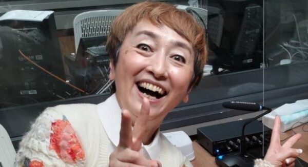 スタジオで笑顔を見せる久本朋子さんのアップ写真、ピースサインが印象的